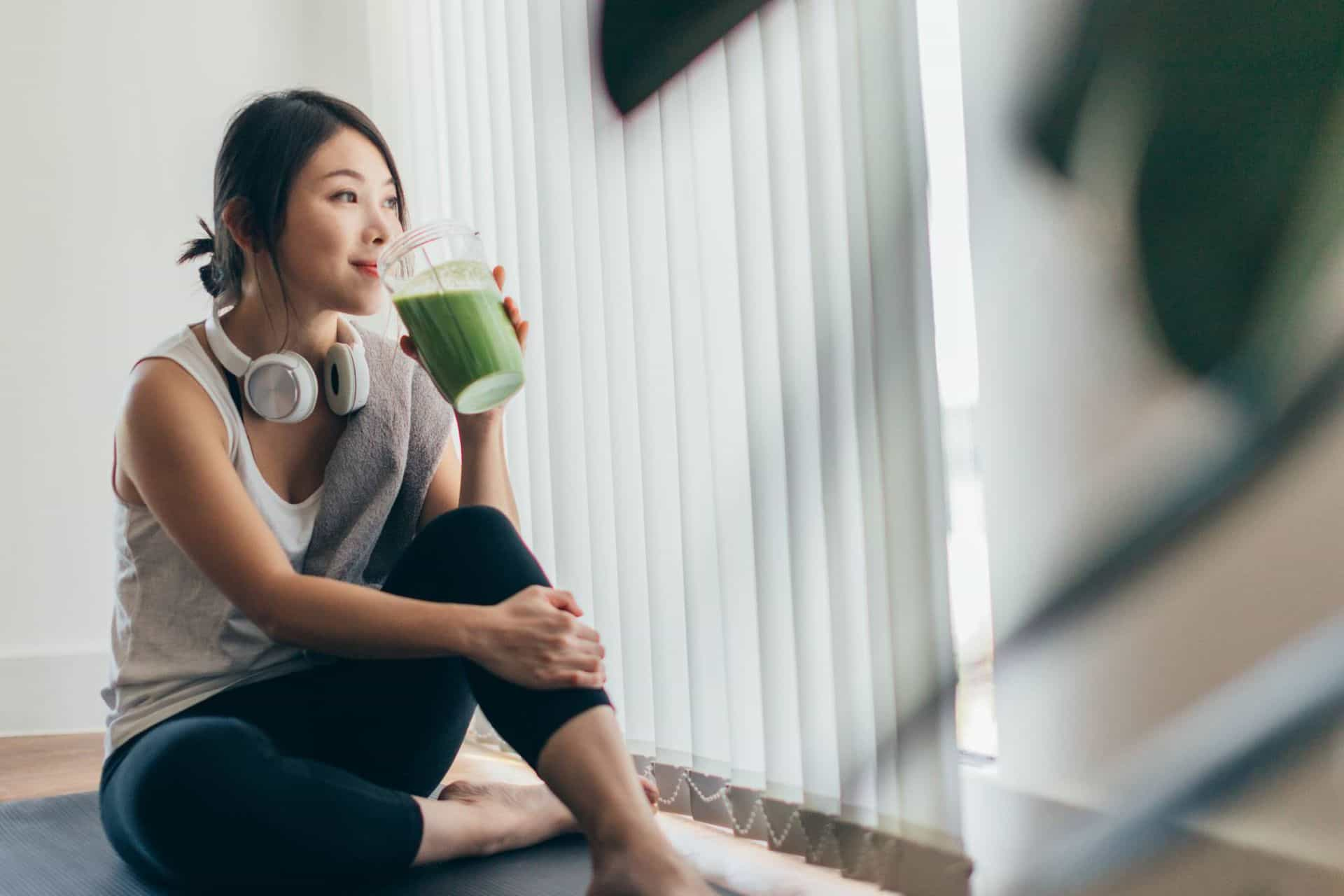 female holding a green smoothie