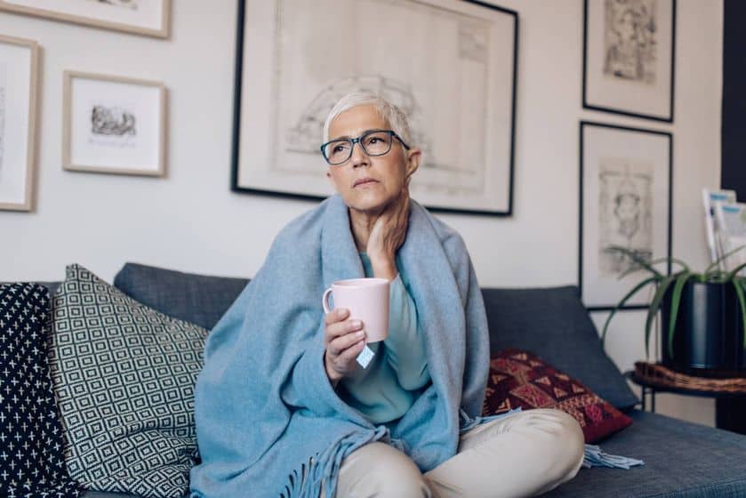 Female wraped in blanket holding a cup of hot tea